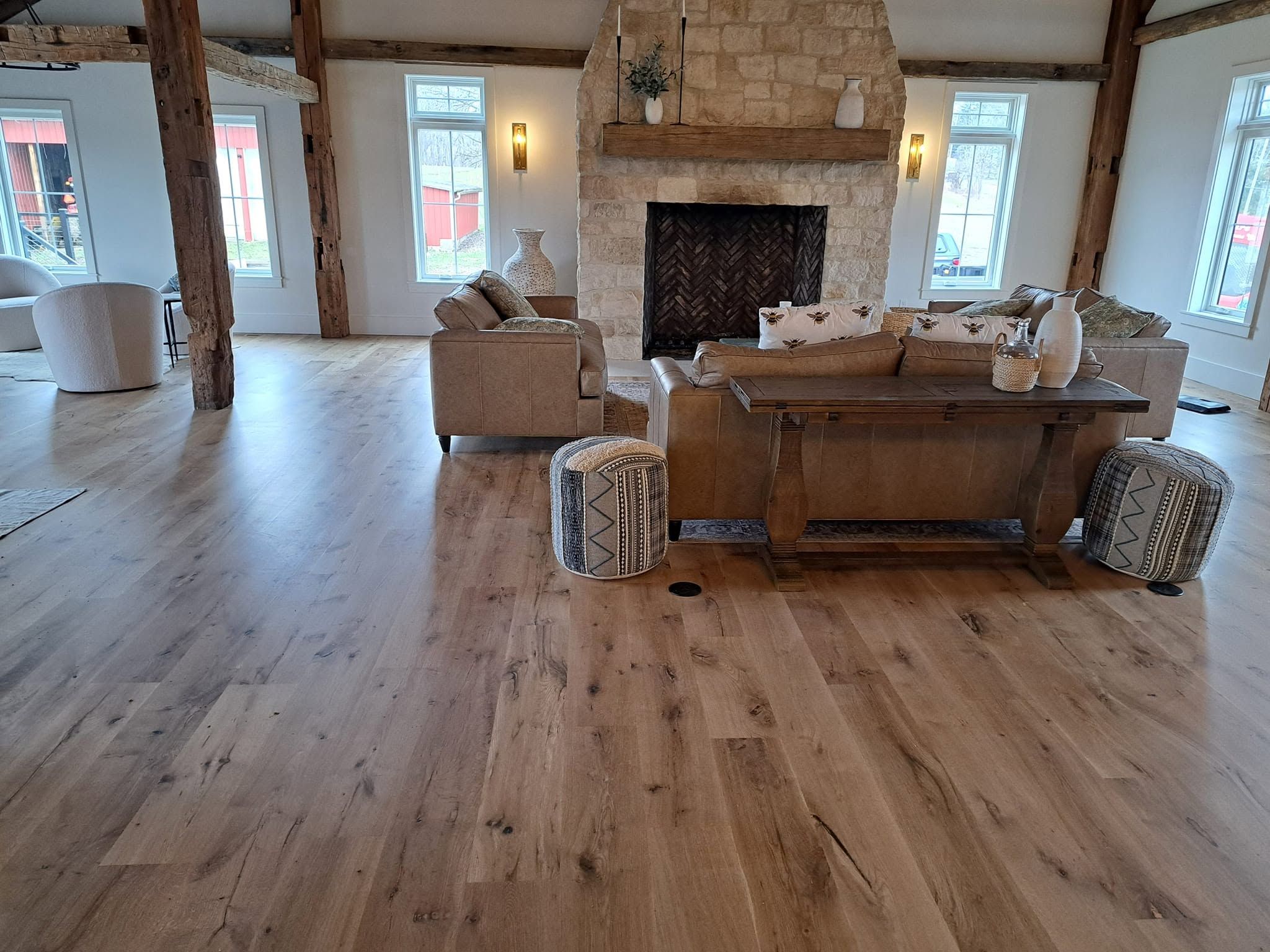 Wide-plank hardwood floor in a timber-frame living room with a stone fireplace