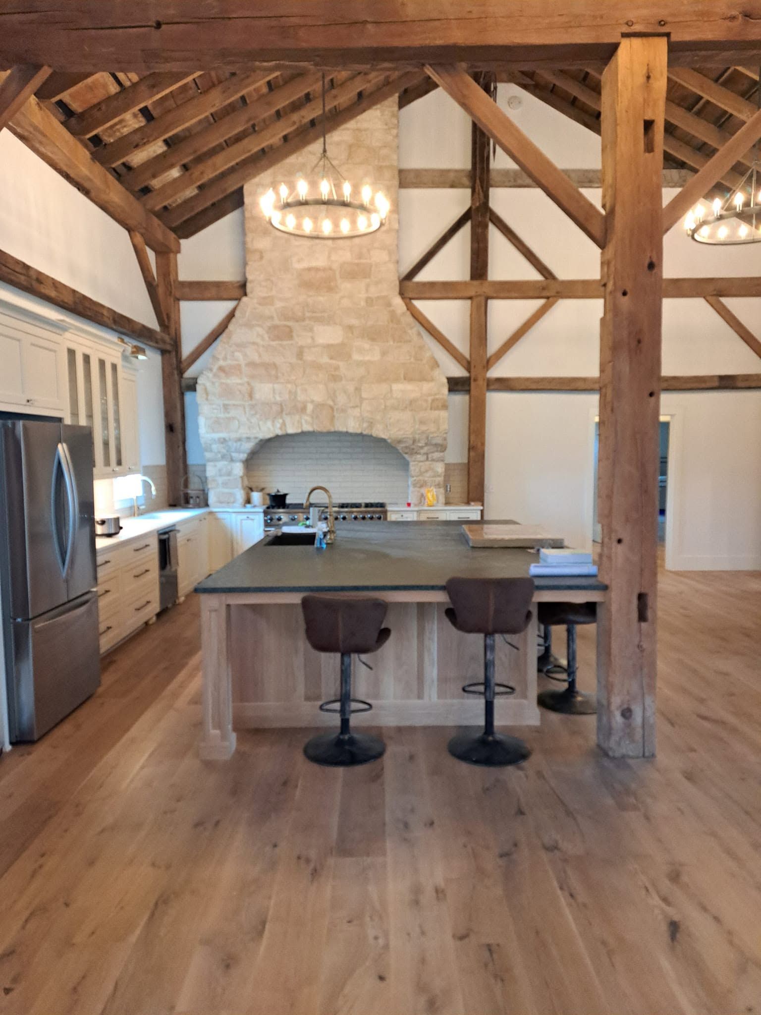 Wide-plank hardwood flooring in an open kitchen with island seating and exposed timber beams